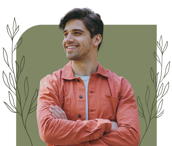 Smiling young man with folded arms wearing an orange jacket in front of a decorative background