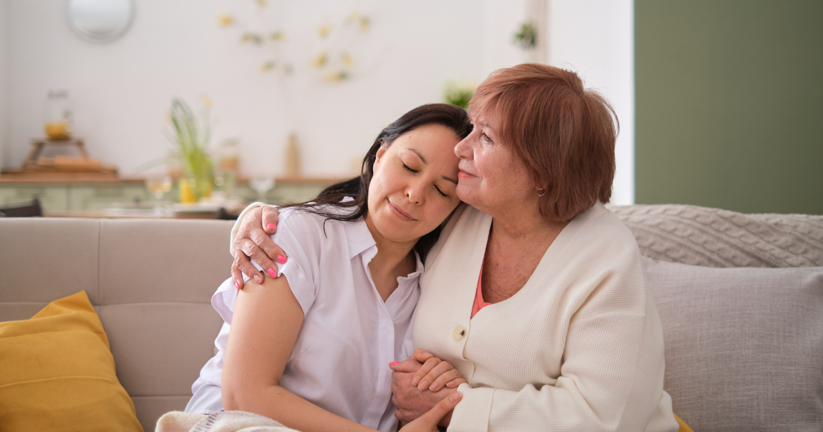 Older woman comforting a younger woman with a supportive hug on a couch